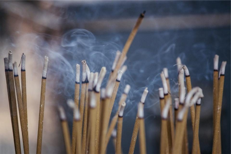 Bâtons d'encens fumants, évoquant l'odeur boisée et fumée du oud